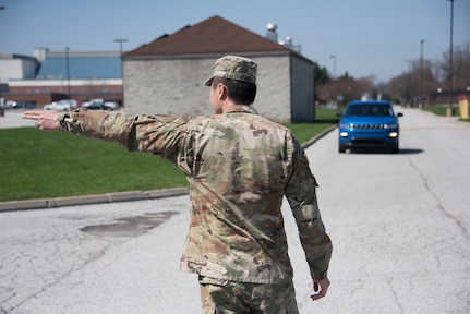 An Indiana National Guard Soldier from the 381st Military Police Company, Plymouth, Indiana, directs traffic at a drive-thru COVID-19 testing site at Merrillville High School, Merrillville, Indiana, April 8, 2020.