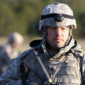 White male in digital grey camouflage helmet and grey jacket and vest.