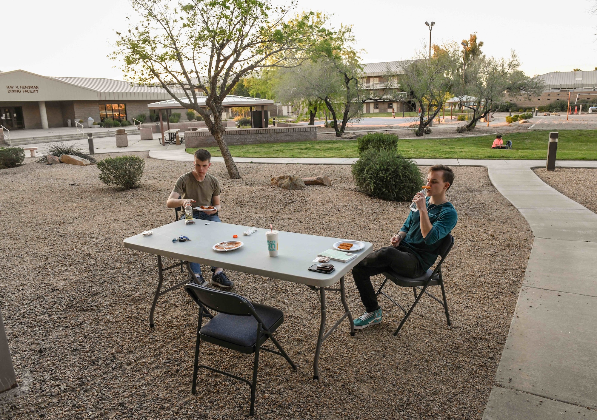 Airman 1st Class Jack Hodnett, 56th Medical Support squadron resource management technician (left), and Airman 1st Class Kody Adams, 56th Component Maintenance Squadron egress maintainer (right) enjoy a complimentary dinner at the Oasis, April 3rd, 2020, at Luke Air Force Base Ariz. The Oasis dinner was held outdoors to adhere to social distancing and preventative health practices. The Oasis is a chapel-sponsored helping organization for dorm Airmen that provides a safe and open environment for Airmen to connect and bond through various activities to include providing home cooked meals. (U.S. Air Force photo by Airman Tyler Jansen)