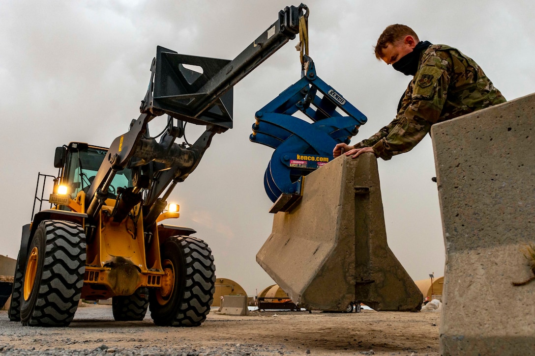 A service member moves a barrier.