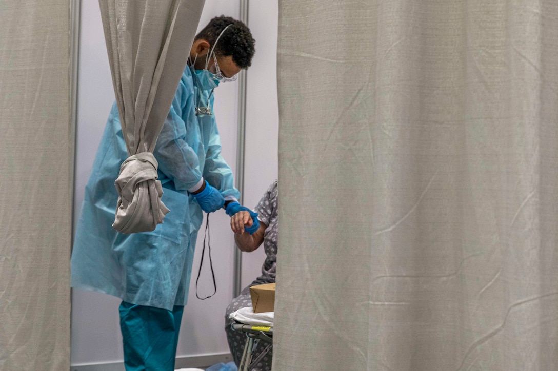 A soldier checks a patient’s pulse.