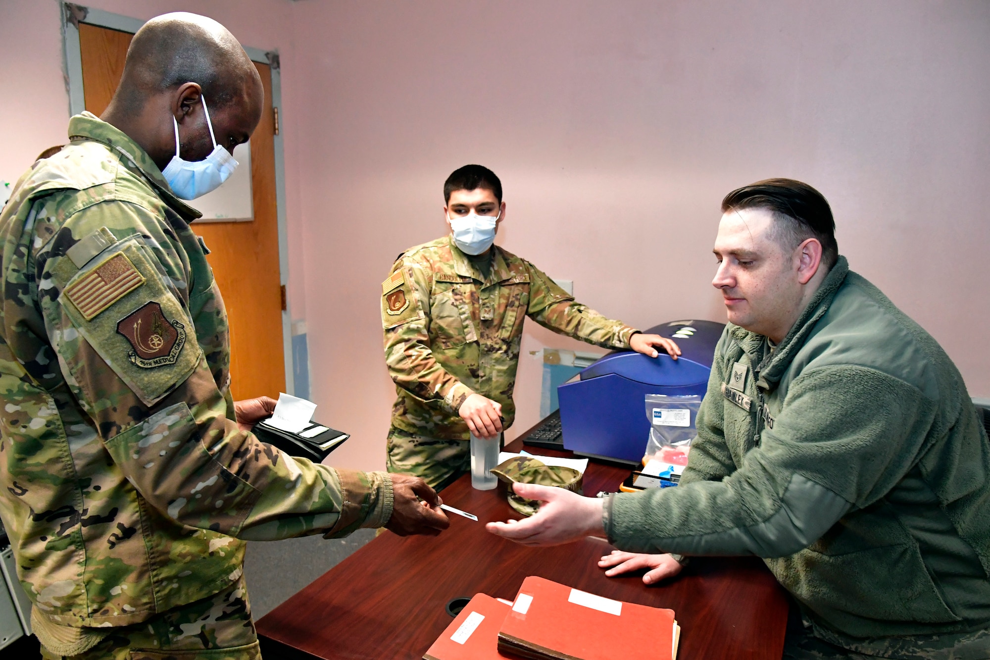 Tech. Sgt. Yves’denis Etiki handing his ID to another Airman during his out processing appointment.