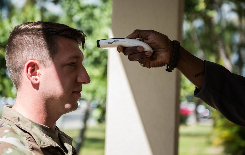 A Soldier gets his temperature checked as part of a new screening process before entering the 613th Air Operations Center on Joint Base Pearl Harbor-Hickam, Hawaii. The new measures are in place to maintain the health and safety of mission essential personnel. These measures include: health screening questions, temperature checks and hand sanitizing. (U.S. Air Force photo by Staff Sgt. Hailey Haux)