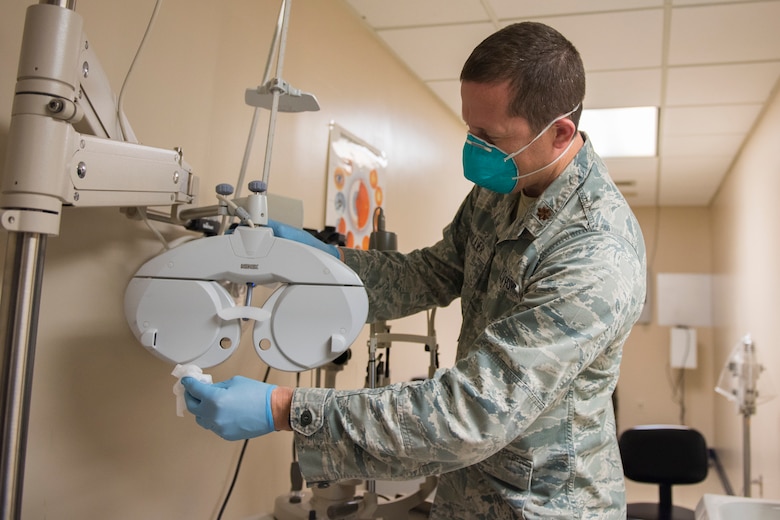 Major Bryan Sixkiller, an optometrist assigned to the 628th Medical Group, Operational Medical Readiness Squadron, cleans equipment at the Optometry Clinic at Joint Base Charleston, S.C., April 7, 2020. Optometry is taking safety measures such as limiting face-to-face time, wearing masks and gloves, frequently washing hands and cleaning medical equipment before and after each examination.