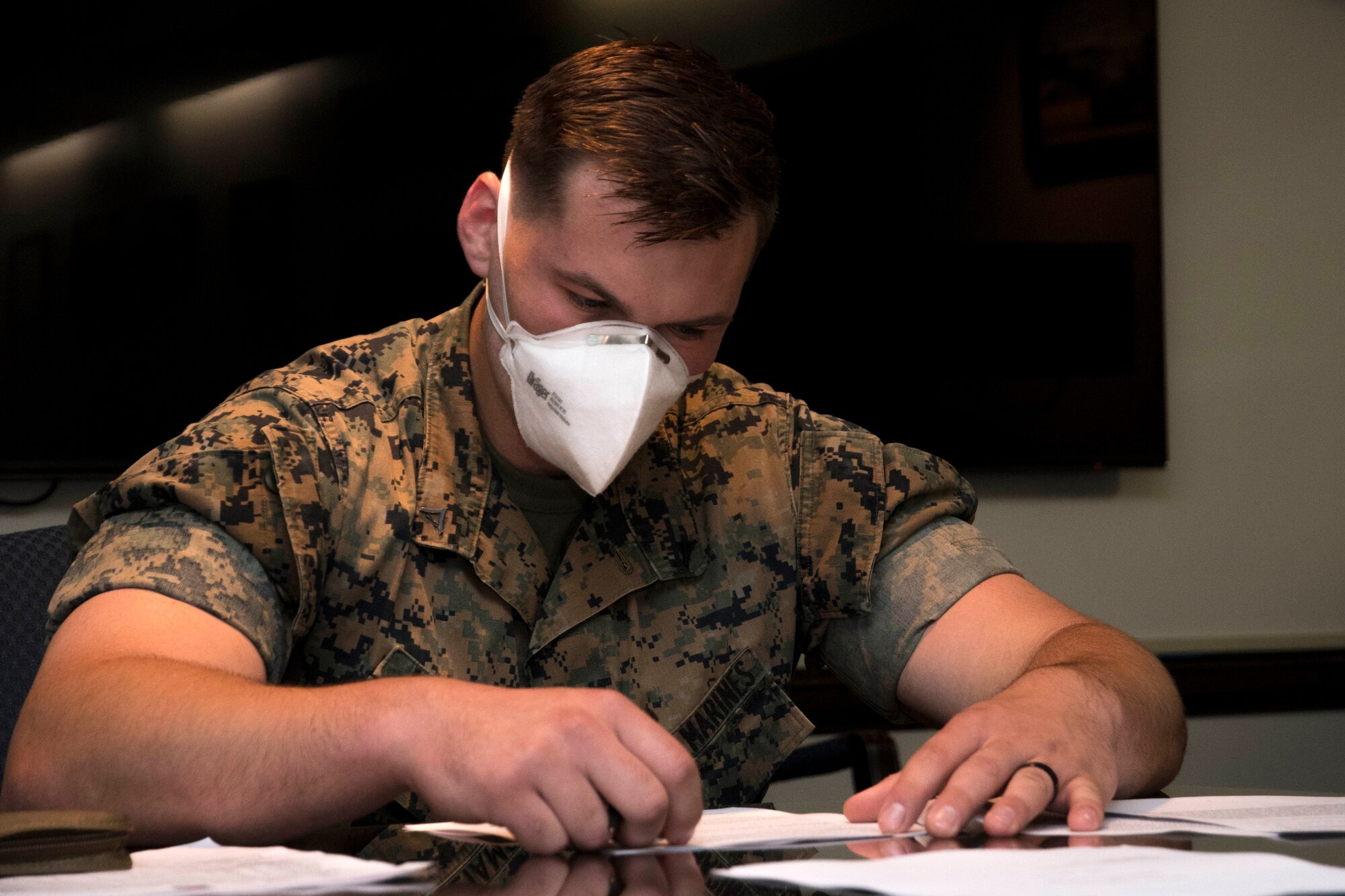 A Marine wears a face mask while completing a legal form worksheet in the wing conference room at Dobbins Air Reserve Base on April 9, 2020. This week, the Dobbins legal office helped more than 60 Marines with legal documents in preparation for a short-notice deployment to assist in the battle against COVID-19. (U.S. Air Force photo/Andrew Park)