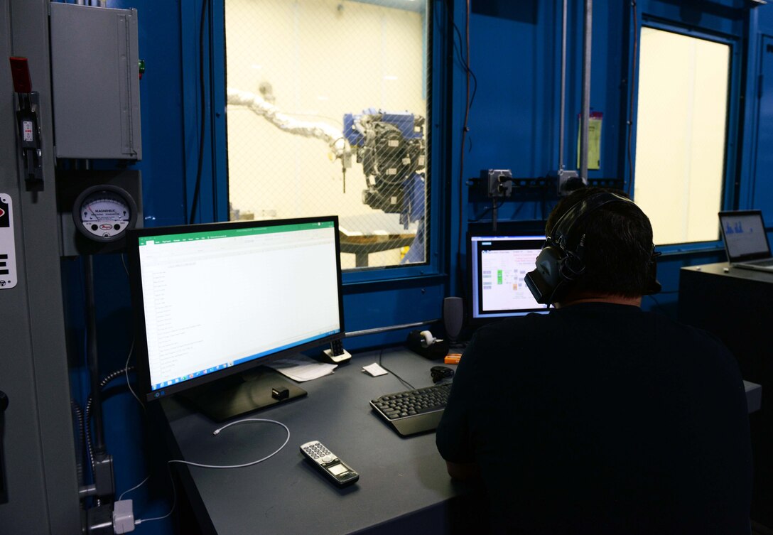 The additive manufacturing facility site manager inputs controls into a cold spray machine.