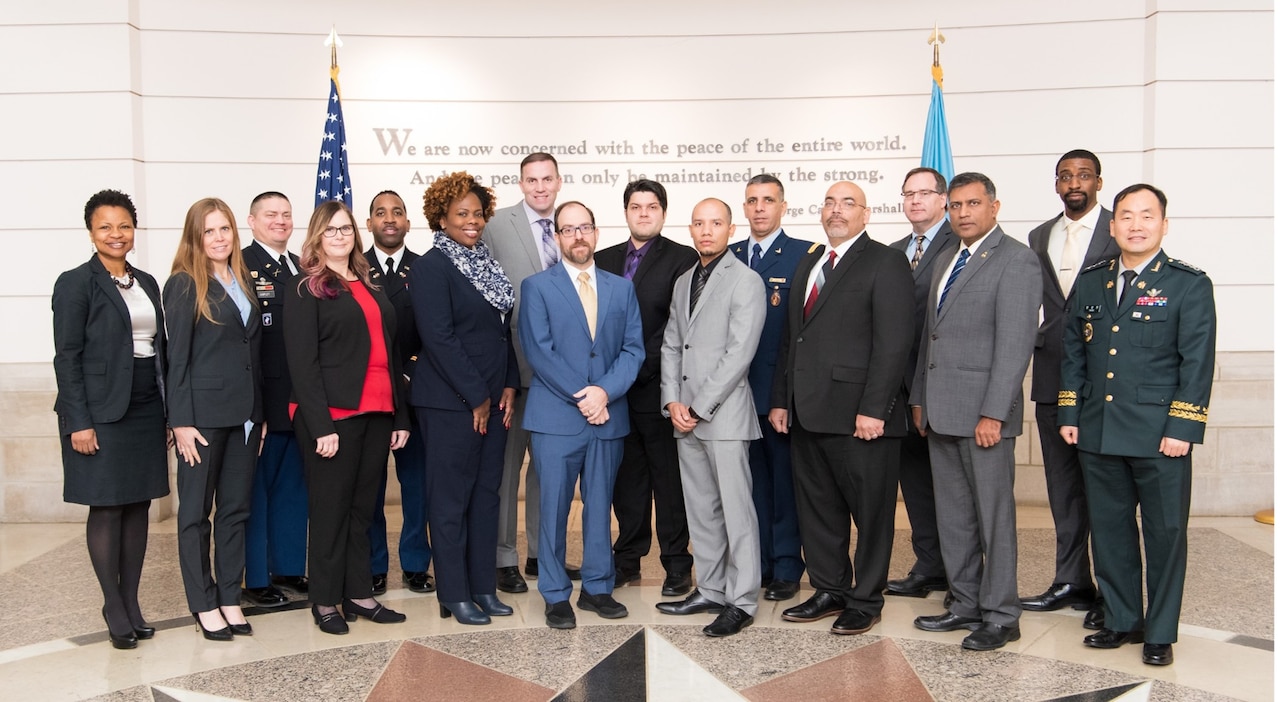 An array of men and women in both military uniforms and civilian clothes stand alongside one another.