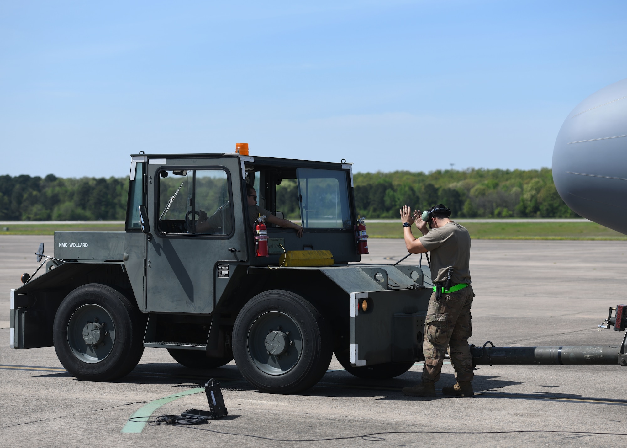 An Airman directs a tow vehicle to a towing hitch.