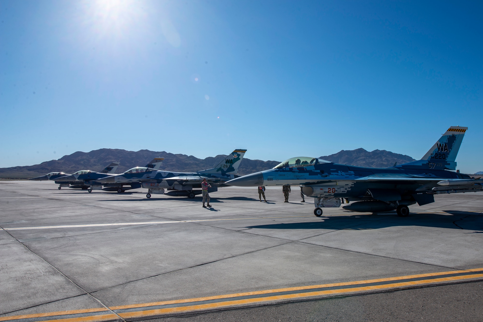 Four F-16 Fighting Falcon fighter jets sit at the end of the runway.