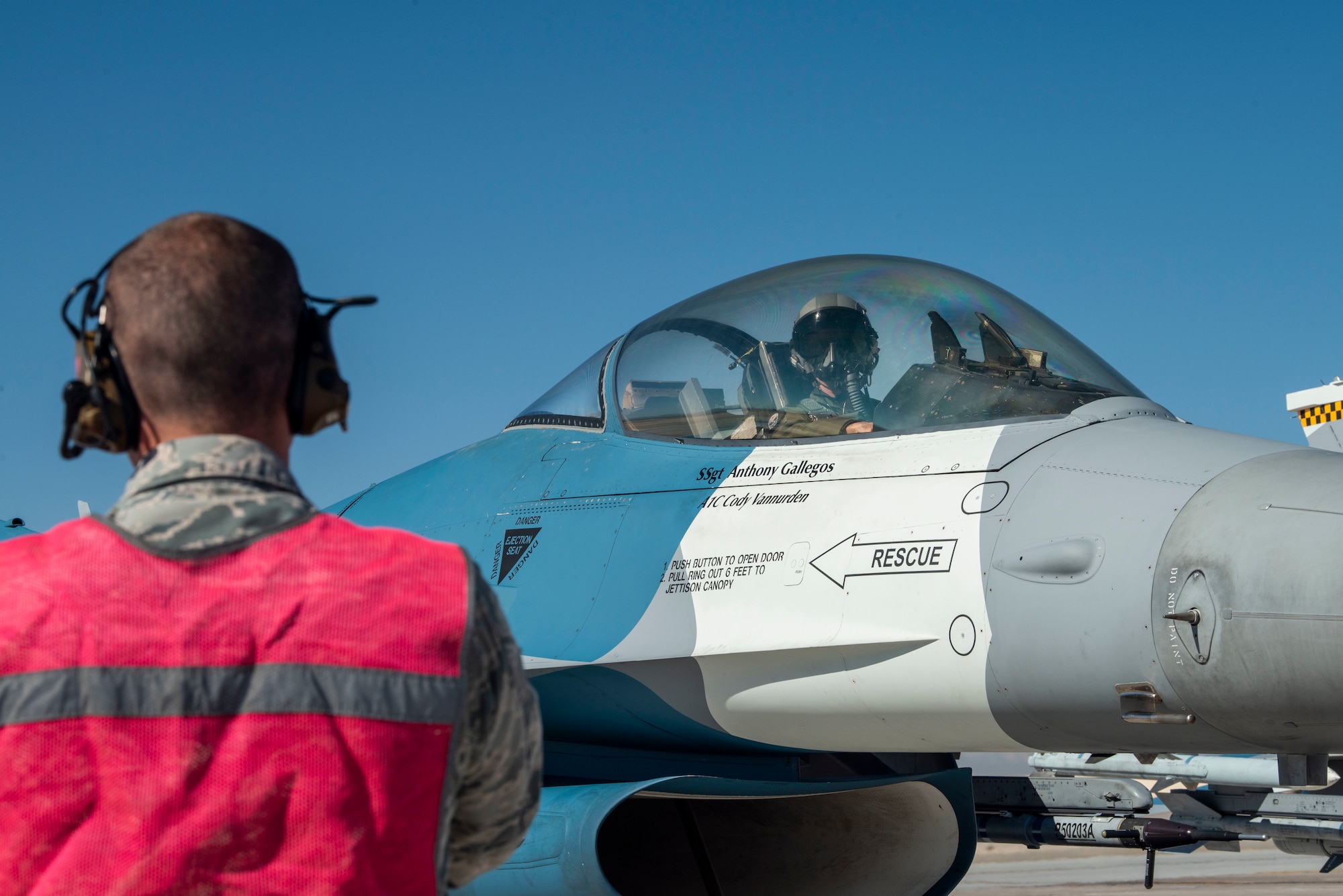 An F-16 Fighting Falcon fighter jet pilot waits for an Airman to signal them.