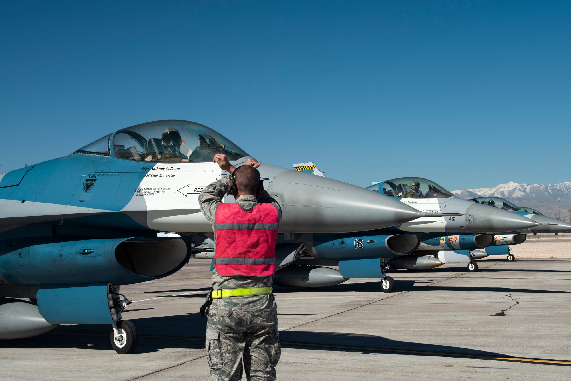 An Airman signals and F-16 Fighting Falcon fighter jet pilot.