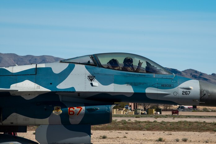 An F-16 Fighting Falcon fighter jet throws up a morale sign with his hand.