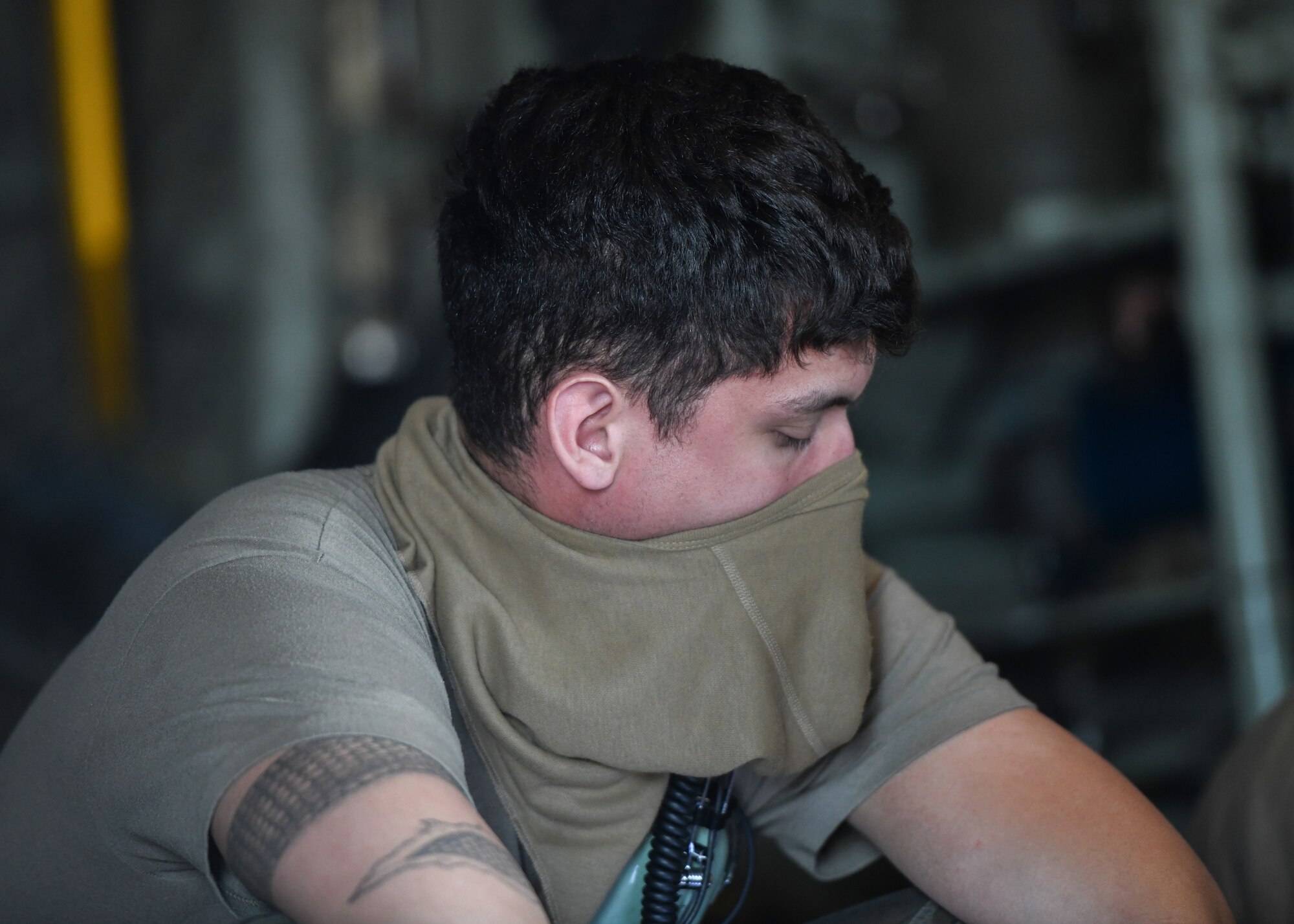 An Airman sits with a mask covering his mouth and nose.