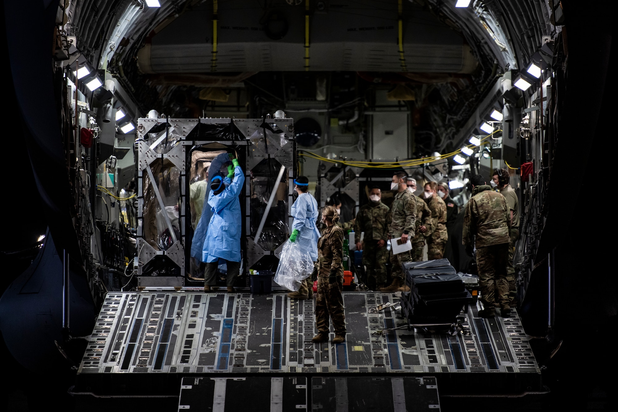 U.S. Air Force Airmen prepare to off-load COVID-19 patients during the first-ever operational use of the Transport Isolation System at Ramstein Air Base, Germany, April 10, 2020. The TIS is an infectious disease containment unit designed to minimize contamination risk to aircrew and medical attendants, while allowing in-flight medical care for patients afflicted by a disease--in this case, COVID-19. (U.S. Air Force photo by Staff Sgt. Devin Nothstine)