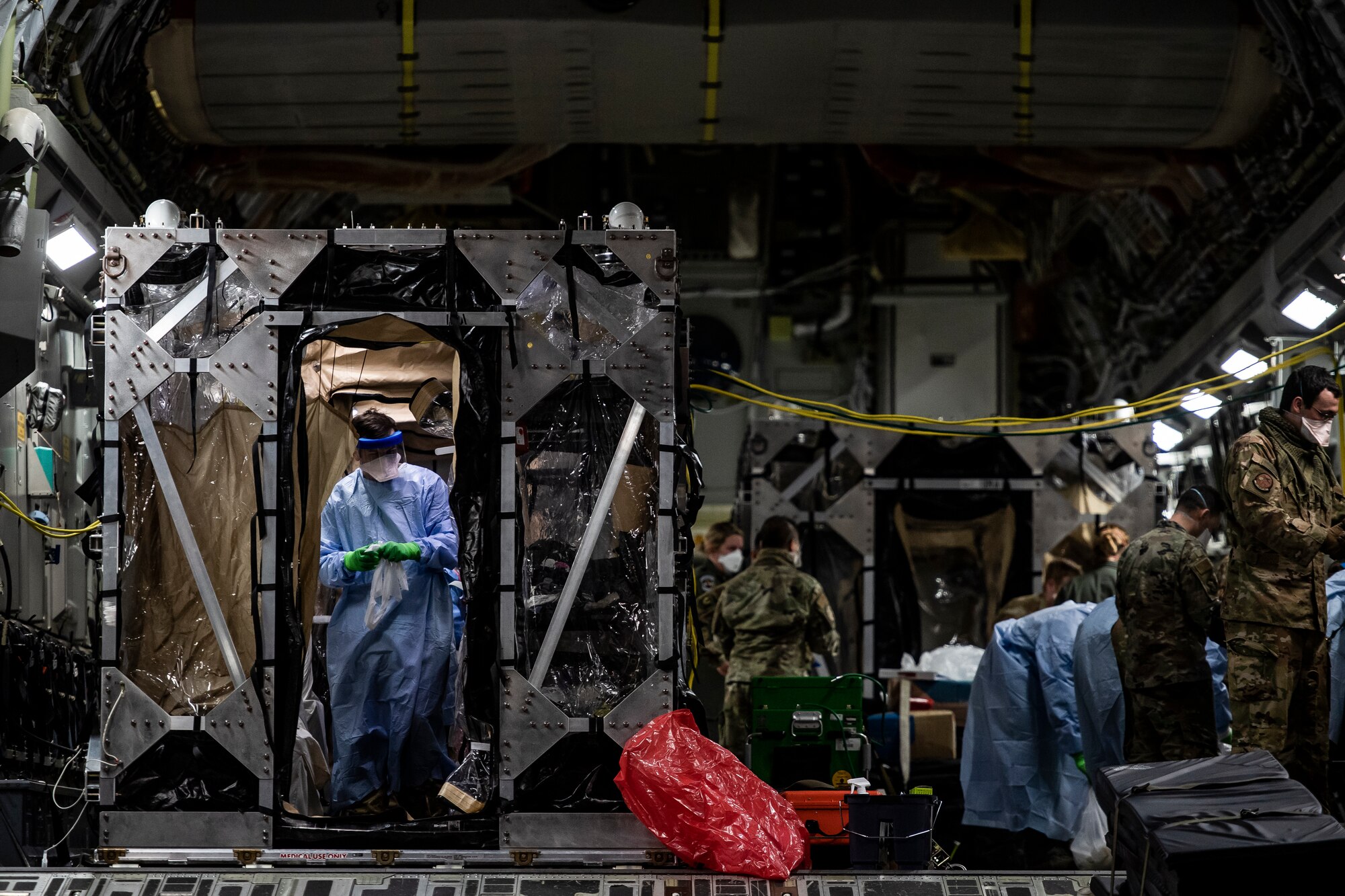 U.S. Air Force Airmen aboard a C-17 Globemaster III aircraft begin disinfecting and decontaminating the aircraft after the first-ever operational use of the Transport Isolation System at Ramstein Air Base, Germany, April 10, 2020. The TIS is an infectious disease containment unit designed to minimize contamination risk to aircrew and medical attendants, while allowing in-flight medical care for patients afflicted by a disease--in this case, COVID-19. (U.S. Air Force photo by Staff Sgt. Devin Nothstine)