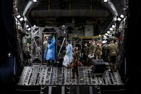 U.S. Air Force Airmen prepare to off-load COVID-19 patients during the first-ever operational use of the Transport Isolation System at Ramstein Air Base, Germany, April 10, 2020. The TIS is an infectious disease containment unit designed to minimize contamination risk to aircrew and medical attendants, while allowing in-flight medical care for patients afflicted by a disease--in this case, COVID-19. (U.S. Air Force photo by Staff Sgt. Devin Nothstine)