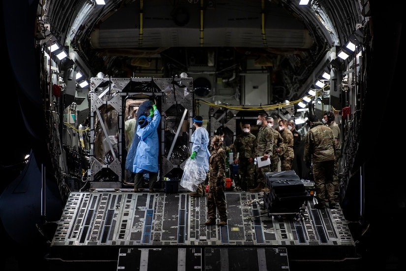 U.S. Air Force Airmen prepare to off-load COVID-19 patients during the first-ever operational use of the Transport Isolation System at Ramstein Air Base, Germany, April 10, 2020. The TIS is an infectious disease containment unit designed to minimize contamination risk to aircrew and medical attendants, while allowing in-flight medical care for patients afflicted by a disease--in this case, COVID-19. (U.S. Air Force photo by Staff Sgt. Devin Nothstine)
