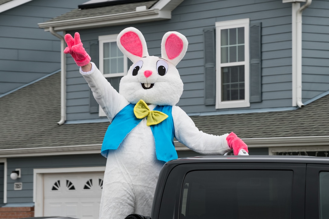The Easter Bunny waves to housing residents of Eagle Heights housing April 10, 2020, at Dover Air Force Base, Delaware. A small caravan of USO volunteers, 436th Security Forces Squadron and Civil Engineer Squadron vehicles, escorted the Easter Bunny around the housing area on Good Friday while observing social distancing to mitigate the spread of COVID-19. (U.S. Air Force photo by Roland Balik)