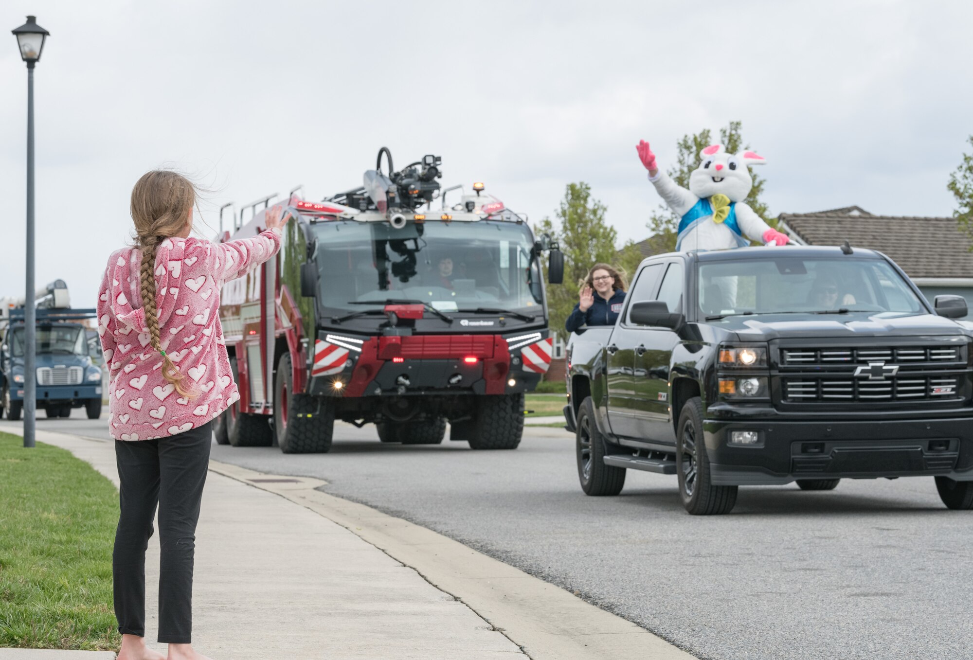 Isabella Goeke, daughter of Lt. Col. Robert Goeke, 436th Contracting Squadron commander, waves to the Easter Bunny in Eagle Heights housing April 10, 2020, at Dover Air Force Base, Delaware.A small caravan of USO volunteers, 436th Security Forces Squadron and Civil Engineer Squadron vehicles, escorted the Easter Bunny around the housing area in a vehicle driven by Staff Sgt. Tate Booms, 436th LRS vehicle maintenance, accompanied by his wife Cassidy, USO Delaware volunteer. On this Good Friday, the Easter Bunny and residents observed social distancing to mitigate the spread of COVID-19. (U.S. Air Force photo by Roland Balik)