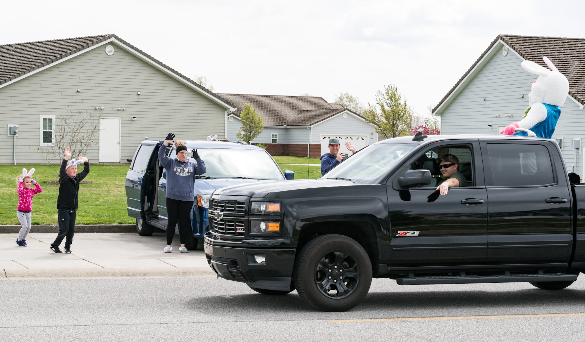 Tech. Sgt. David Miller, 436th Maintenance Group weapon systems controller, along with his family, wave to the Easter Bunny as he passes their vehicle in Eagle Heights housing April 10, 2020, at Dover Air Force Base, Delaware. A small caravan of USO volunteers, 436th Security Forces Squadron and Civil Engineer Squadron vehicles, escorted the Easter Bunny around the housing area in a vehicle driven by Staff Sgt. Tate Booms, 436th LRS vehicle maintenance, accompanied by his wife Cassidy, USO Delaware volunteer. On this Good Friday, the Easter Bunny and residents observed social distancing to mitigate the spread of COVID-19. (U.S. Air Force photo by Roland Balik)