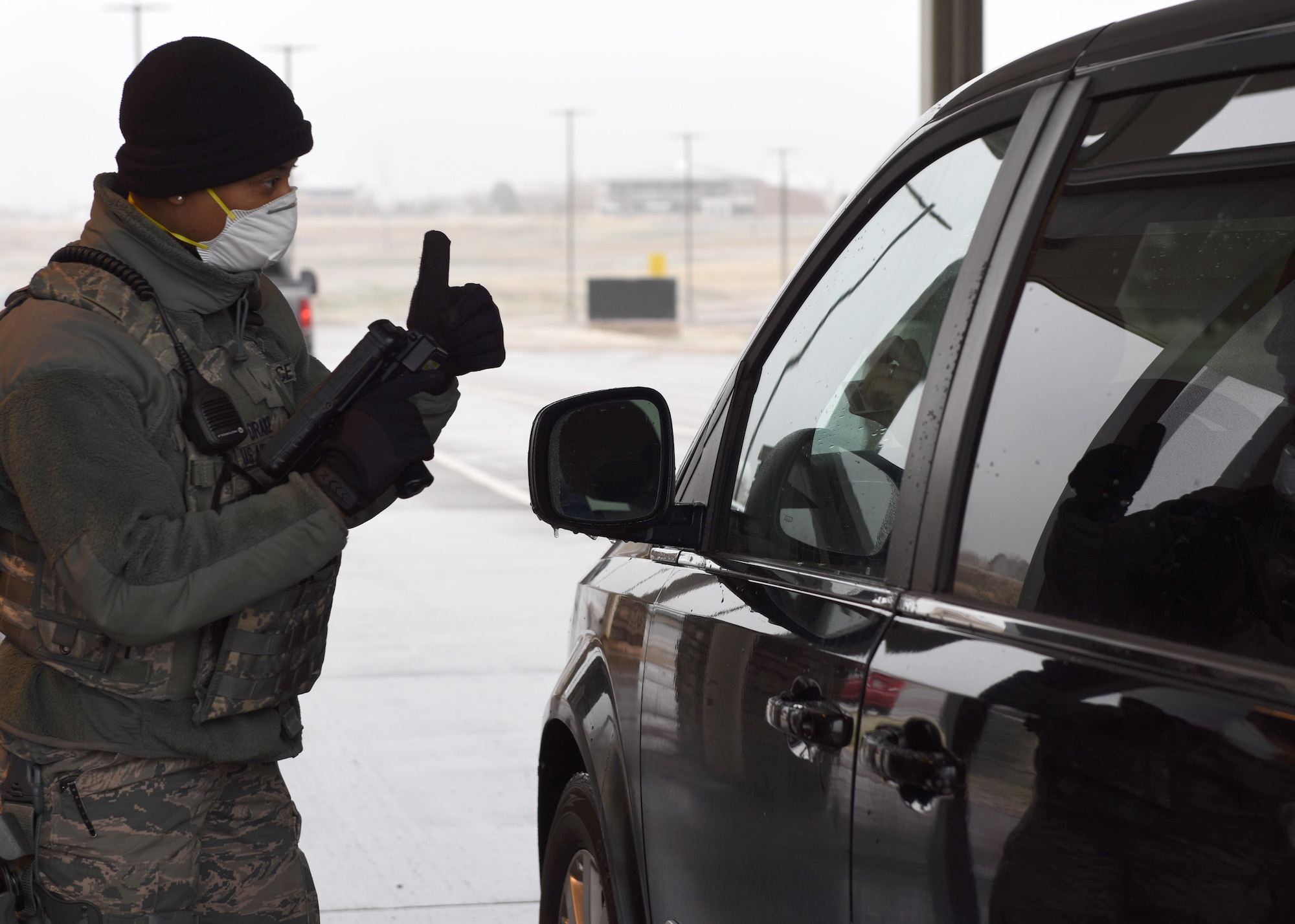 U.S. Air Force Airman 1st Class Laurente Drake, 460th Security Forces Squadron member, gives approval for a driver to proceed through the Mississippi Gate at Buckley Air Force Base, Colo., April 2, 2020. Buckley AFB is currently in Health Protection Condition level Charlie in response to the spread of COVID-19 in the state of Colorado. In efforts to reduce the amount of face-to-face interaction, identification cards are now visually inspected or scanned at a distance upon arrival to the gate unless absolutely required for security or privacy reasons. The HPCON Charlie defines base measures for a substantial disease threat and ensures Team Buckley is using the proper protocols and processes to prevent transmission. (U.S. Air Force photo by Airman 1st Class Haley N. Blevins)