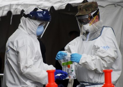 A Soldier from the 126th Aviation Battalion, Massachusetts Air National Guard, helps administer COVID-19 tests to first responders at a drive-thru testing facility, April 9, 2020, on the Big E fairgrounds in West Springfield, Massachusetts. The soldiers worked with other Massachusetts agencies at the site.