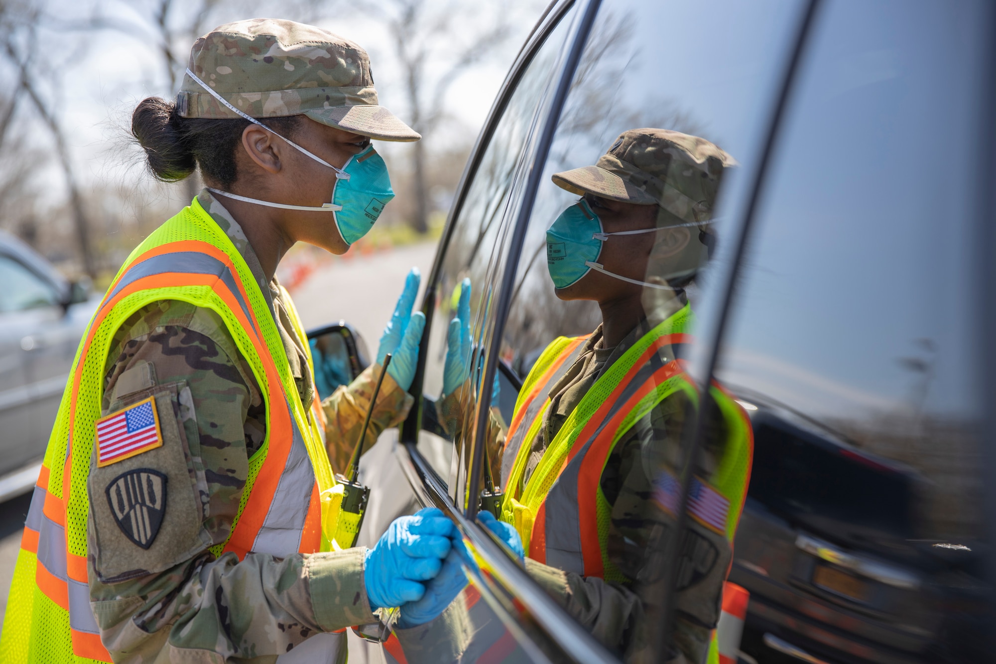 Spc. Gilliam-Gray Shawnese with the 101st Expeditionary Signal Battalion, 369th Sustainment Brigade, New York Army National Guard, gives instructions to people in their vehicle at the COVID-19 Mobile Testing Center in Glenn Island Park, New Rochelle, Apr. 8, 2020. The New York National Guard continues support at seven drive-thru testing sites.