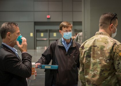 U.S. Air Force Col. Sean Brennan, center, 103rd Medical Group commander and Hartford Hospital operations manager for alternative care sites, speaks with Connecticut National Guard members and local officials at the Connecticut Convention Center in Hartford, April 11, 2020. Brennan is helping lead the Hartford region’s response to the COVID-19 pandemic through his civilian role with Hartford HealthCare, where he works full time as a physician assistant-certified.