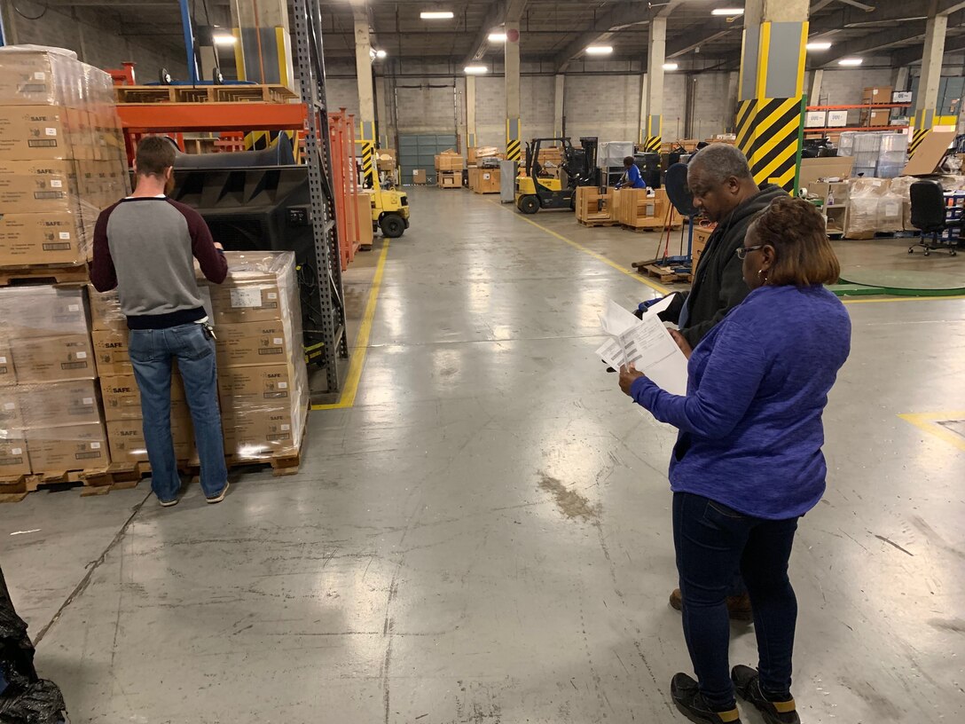 Deborah Jackson (right), a project manager for the Defense Security Cooperation Agency at Albany, Georgia, and her colleagues Robert Brantley (center), a material expeditor, and Jeremy Sexton, a project supervisor, begin to inventory, prepare, and palletize the 154,000 N95 masks to prepare them for shipment.