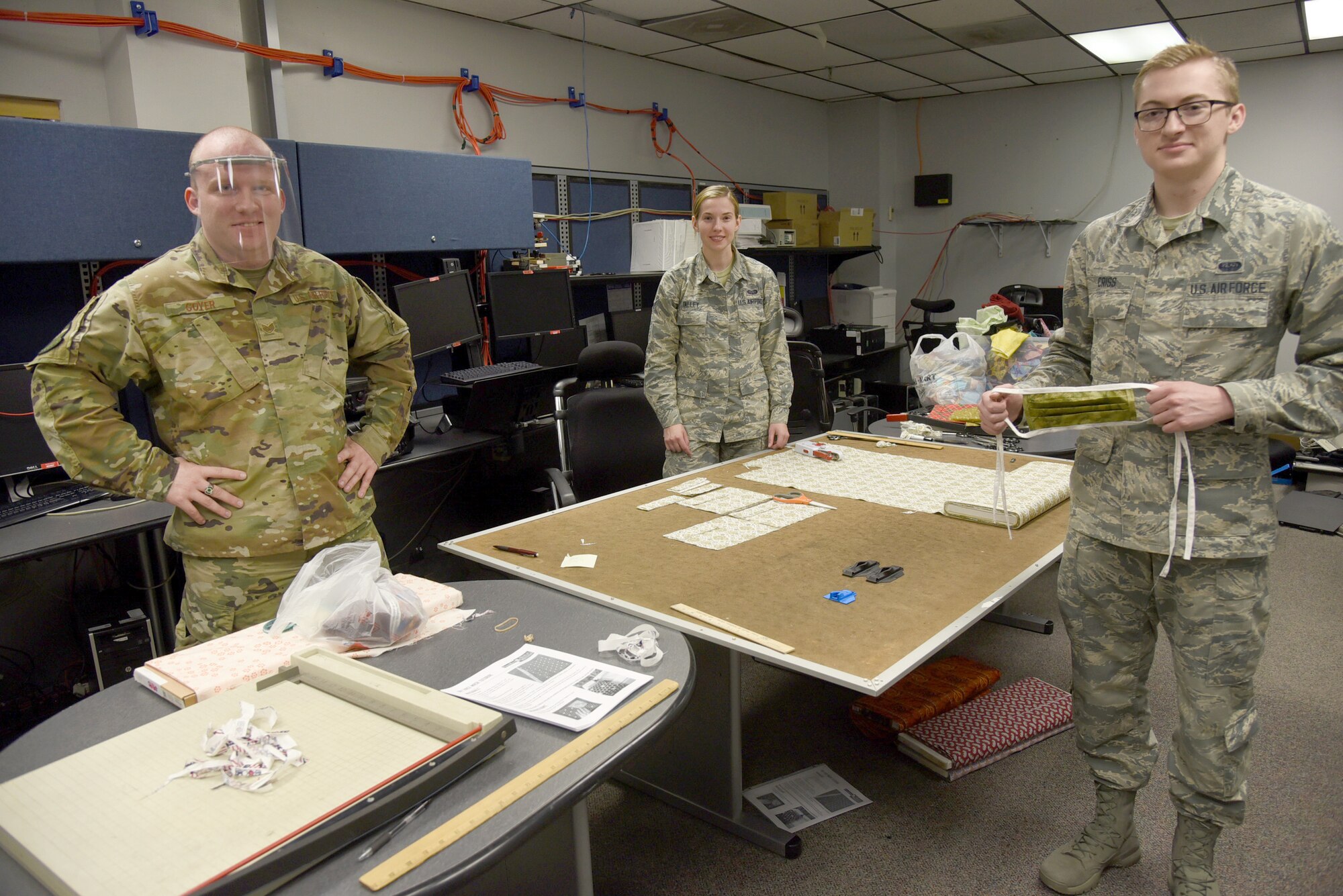 Staff Sgt. Zachary Goyer, Airman First Class Sarah Talley and Airman First Class Stephen Criss, with the 552nd Air Control Network Squadron, are volunteering their time and resources to make fabric masks and 3-D printed clips for plastic face shields. They're working with at least 16 military and spouse volunteers. A local company, donated fabric and materials to their cause. The Airmen have already donated over 48 of the 3-D printed clips and shields and several fabric masks to local hospice organizations, and have more ready to go. (U.S. Air Force photo/Kelly White)