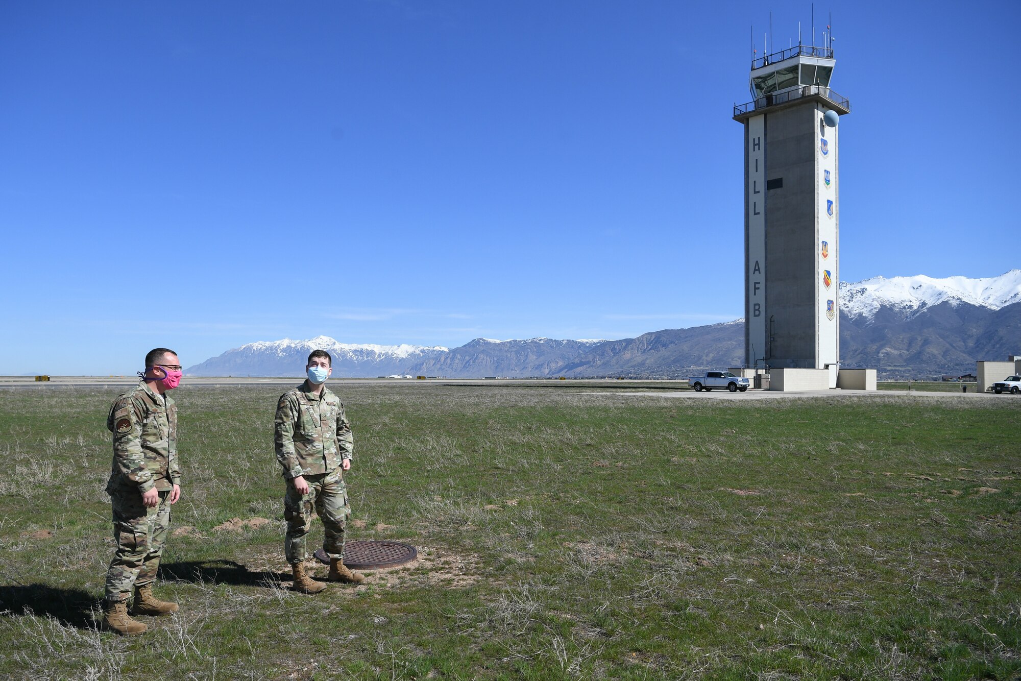 Airmen from the weather shop stand outside with the air traffic control tower visible in the background.