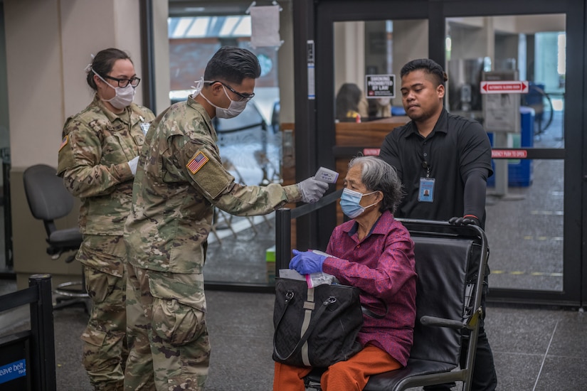 Soldier takes temperature of woman at airport.