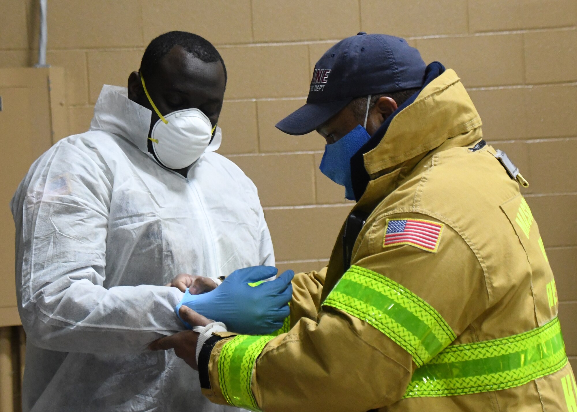 State Hazmat technicians help Soldiers from the 26th Maneuver Enhancement Brigade Headquarters and Headquarters Company and the 126th Aviation Battalion properly put on their Personal Protective Equipment before helping to administer COVID-19 tests to first responders at a drive thru testing facility, April 9, 2020, on the Big E fairgrounds in West Springfield, Massachusetts. The soldiers worked with other Massachusetts agencies getting individuals tested. The tested individuals should have their results digitally within 48 hours. (U.S. Air National Guard photo by Airman 1st Class Sara Kolinski)