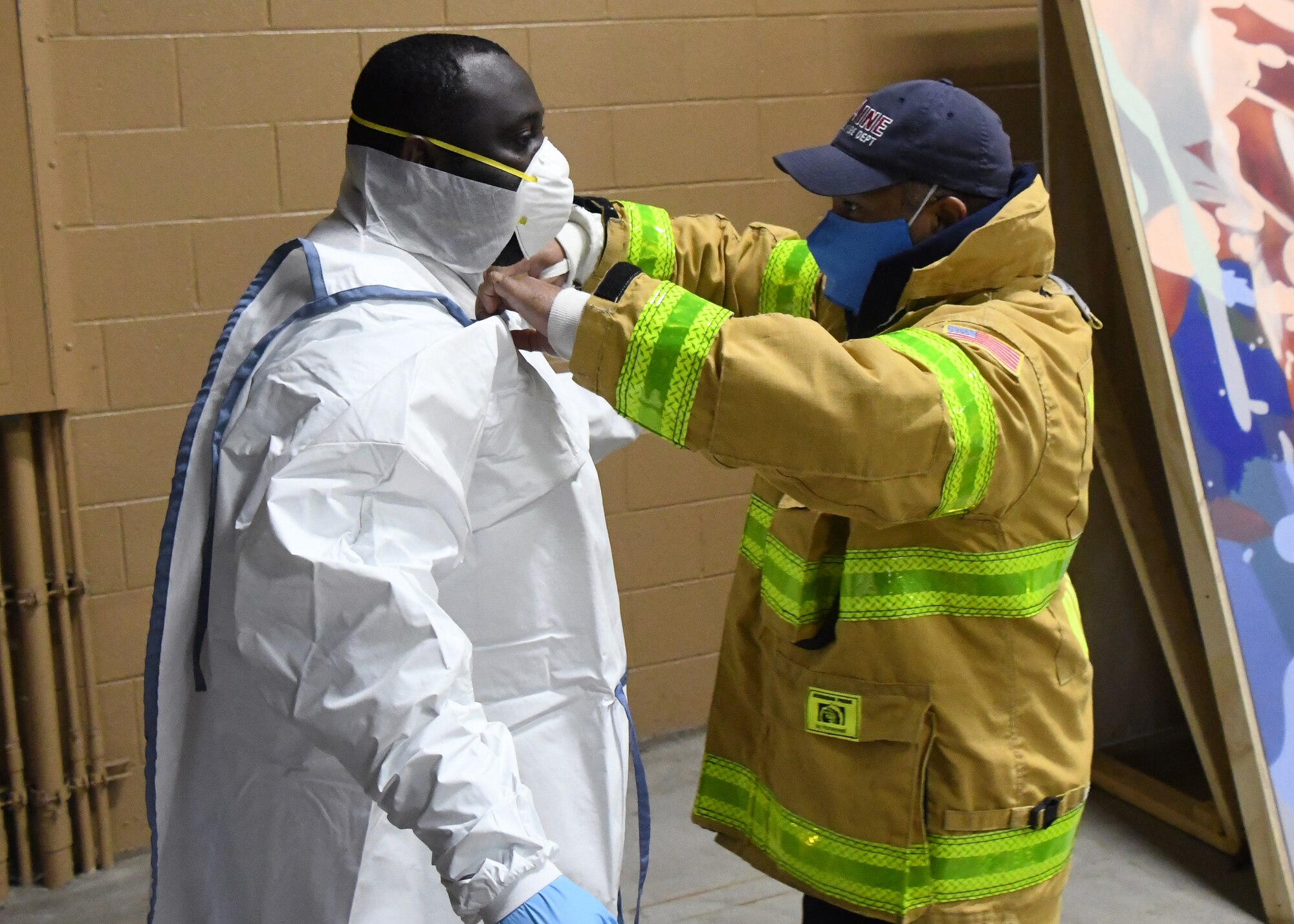 State Hazmat technicians help Soldiers from the 26th Maneuver Enhancement Brigade Headquarters and Headquarters Company and the 126th Aviation Battalion properly put on their Personal Protective Equipment before helping to administer COVID-19 tests to first responders at a drive thru testing facility, April 9, 2020, on the Big E fairgrounds in West Springfield, Massachusetts. The soldiers worked with other Massachusetts agencies getting individuals tested. The tested individuals should have their results digitally within 48 hours. (U.S. Air National Guard photo by Airman 1st Class Sara Kolinski)