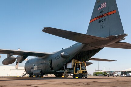 U.S. Air Force Airman 1st Class Evan Spotloe, foreground, a loadmaster, and Staff Sgt. Seth Johnson, a flight engineer, both with the 169th Airlift Squadron, Illinois Air National Guard, help load medical isolation pods into a C-130H Hercules in Eugene, Ore., April 8, 2020. Two 182nd Airlift Wing C-130 aircrews airlifted 250 isolation pods in a cross-country overnight homeland defense mission delivery to Chicago for use in an alternate medical facility.