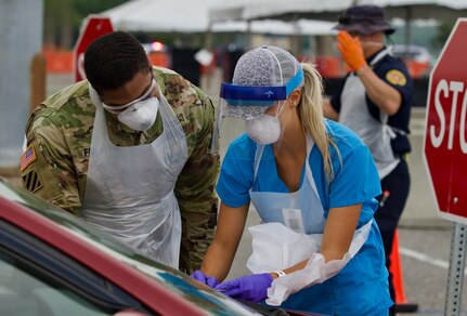 A Florida National Guard Soldier works alongside a nurse as he learns the processes at Jacksonville’s COVID-19 community-based testing site at TIAA Bank Field, April 13, 2020. The FLNG's 3rd Battalion of the 20th Special Forces Group (Airborne) is taking over operation of the site.