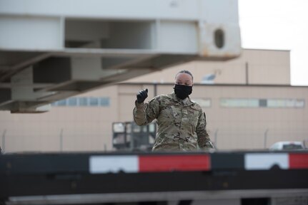 Senior Airman Tracy Turner, a spotter from the 635th Materiel Maintenance Group -- the Air Force’s only Basic Expeditionary Airfield Resources unit – guides a forklift operator putting a cargo container onto a flatbed truck, April 9, 2020, on the BEAR Base ramp on Holloman Air Force Base. Within 48 hours of notification, the 635th MMG loaded more than 30 trucks with 1.2 million pounds of equipment and cargo to support Joint Base-San Antonio’s contingency billeting capability during the COVID-19 crisis. This vital equipment will help ensure that the Air Force’s basic training pipeline will endure throughout the spectrum of the COVID-19 response. (U.S. Air Force photo by Tech. Sgt. Matthew Rosine)