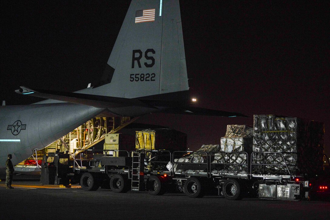 Airmen unload an aircraft at night.