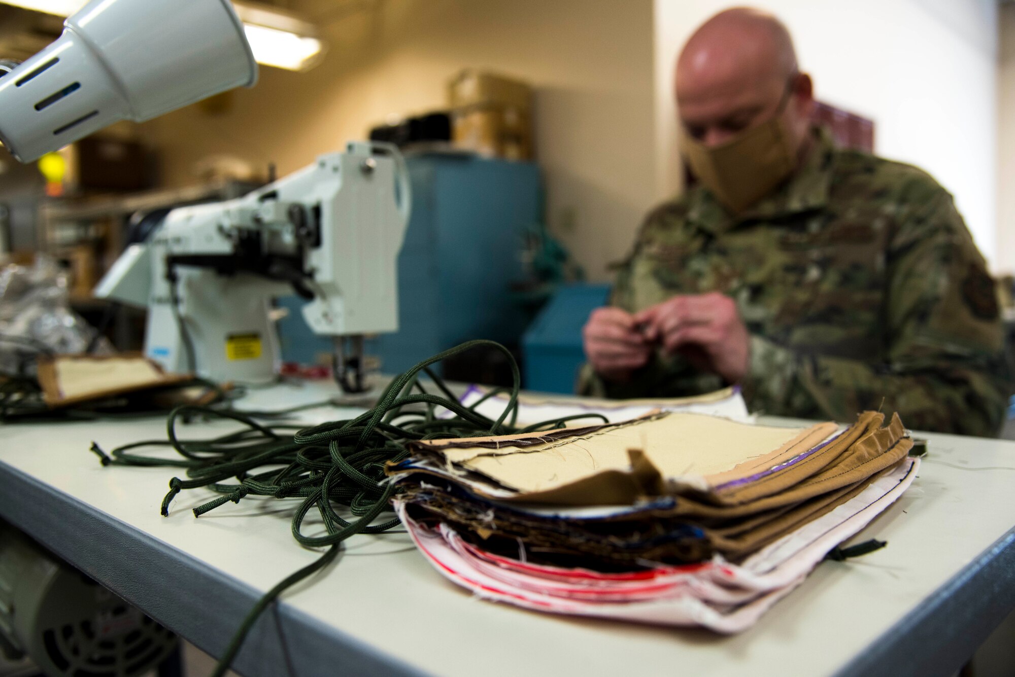 U.S. Air Force Master Sgt. Shawn Freed, 92nd Operation Support Squadron Aircrew Flight Equipment superintendent, prepares a new stack of protective facemasks to sew and create for Airmen to wear at Fairchild Air Force Base, Washington, April 10, 2020. So far, AFE have produced over 650 protective facemasks for Airmen on the installation to wear. (U.S. Air Force photo by Senior Airman Jesenia Landaverde)