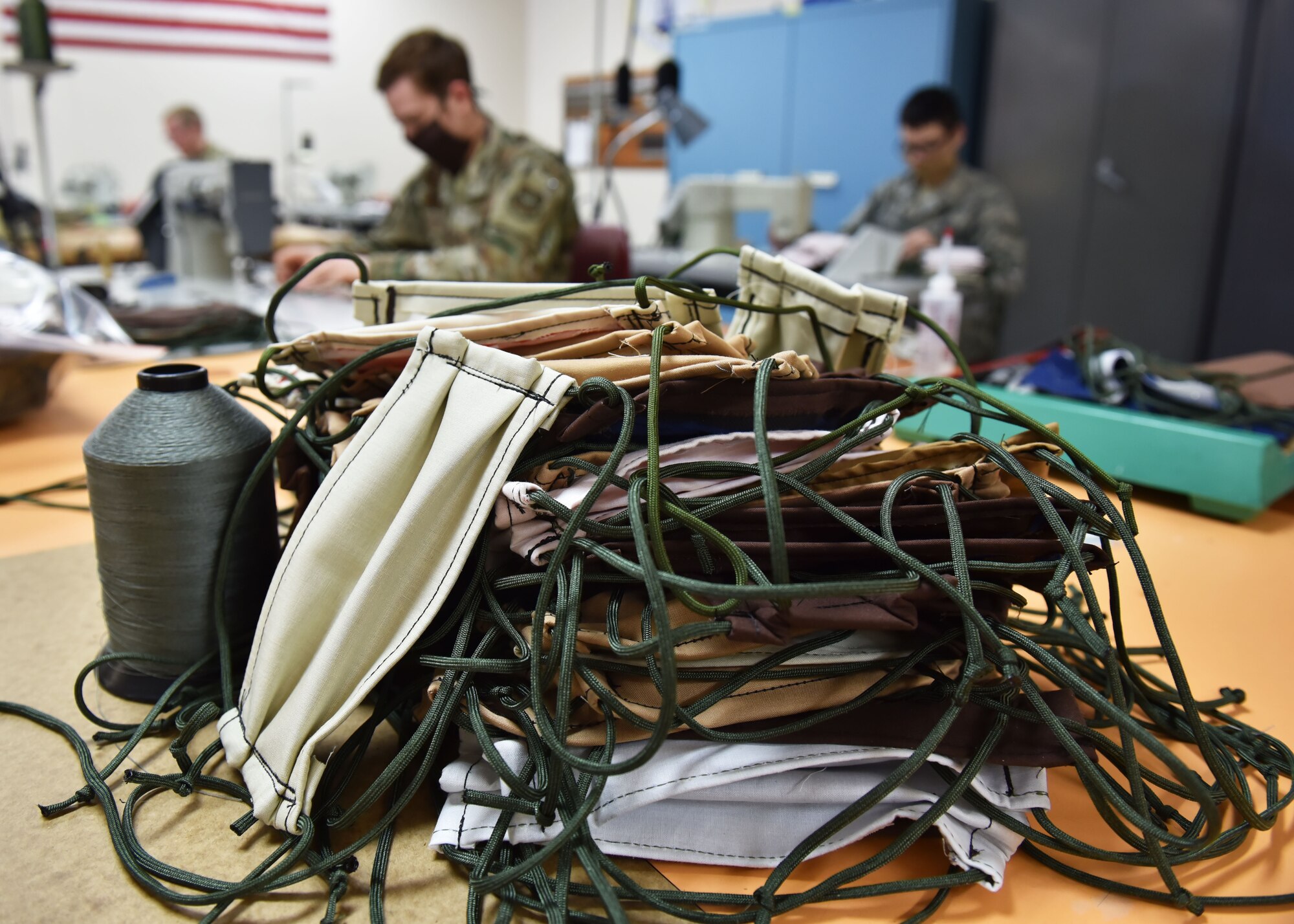 Finished Protective facemasks created by 92nd Operation Support Squadron Aircrew Flight Equipment Airmen rest on a table to be distributed at Fairchild Air Force Base, Washington, April 10, 2020. The mass mask production comes after the secretary of defense released a policy stating that all individuals including military personnel, civilian employees, family members and contractors on Department of Defense property, installations and facilities, must wear cloth face coverings where physical distancing measures are difficult to maintain. (U.S. Air Force photo by Senior Airman Lawrence Sena)