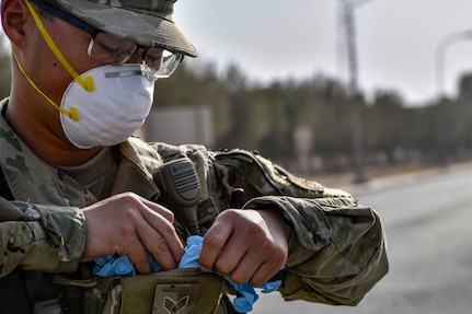 An airmen wearing a facemask removes gloves from his supplies.