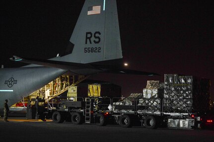 Airmen unload an aircraft at night.