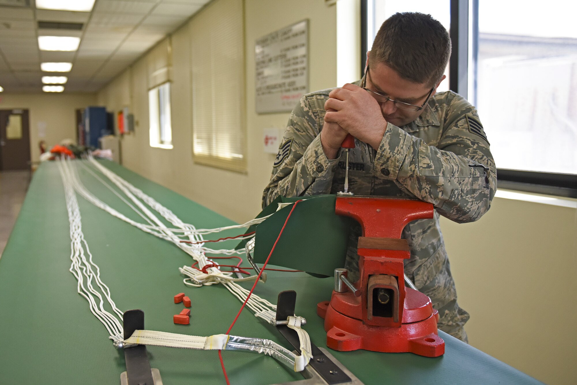 U.S. Air Force Staff Sgt. Nathaniel Armbruster, 8th Operations Support Squadron aircrew flight equipment NCO in charge, repairs a parachute canopy at Kunsan Air Base, Republic of Korea, April 13, 2020. AFE Airmen are responsible for inspecting, maintaining and servicing all equipment aircrew members require while performing their duties. (U.S. Air Force photo by Staff Sgt. Mackenzie Mendez)