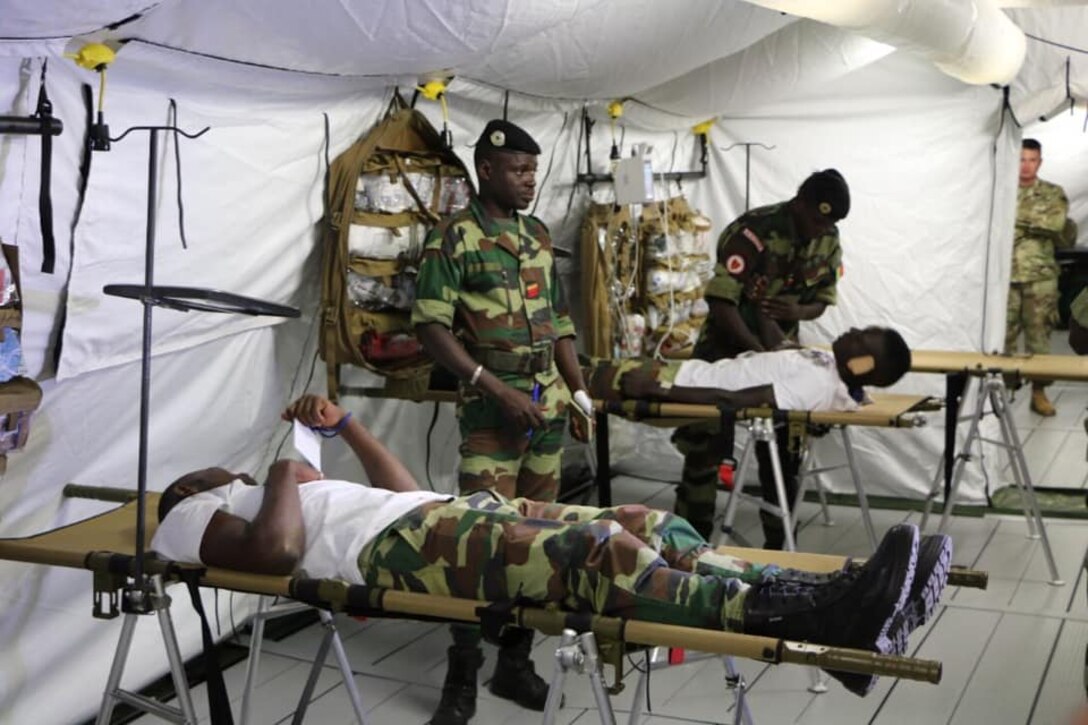 Two Senegalese soldiers stand as two others lie on cots during training for setting up a mobile hospital.