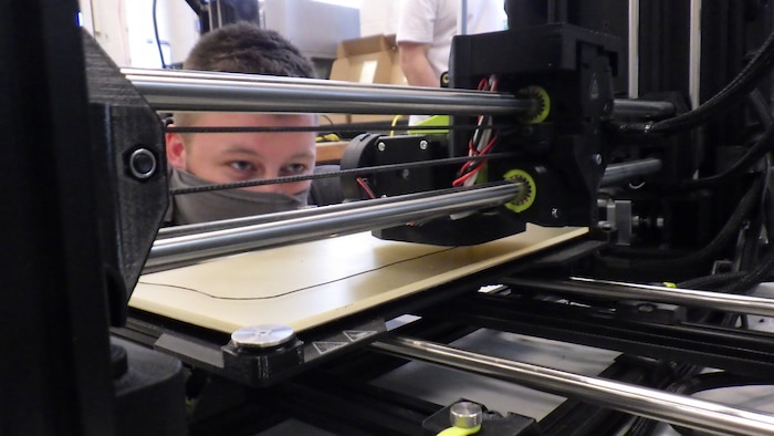 Zach Heinkel, an engineer in the Additive Manufacturing Project Office, watches an extrusion bead of a 3D printer as it makes a face mask frame on April 10, 2020, in the Additive Manufacturing Lab at Naval Surface Warfare Center Carderock Division in West Bethesda, Md.