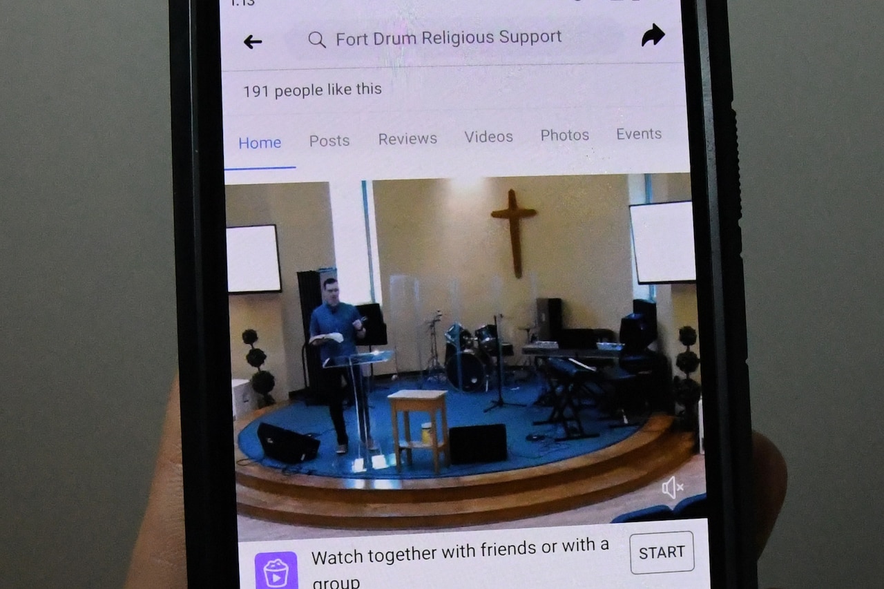 The screen of a smartphone shows a religious service being broadcast on Facebook.