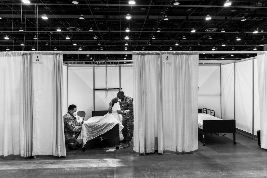 Two soldiers work inside of a makeshift hospital room.