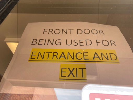 A sign is displayed at the front of the commissary on Goodfellow Air Force Base, Texas, April 14, 2020. Due to COVID-19 safety measures the commissary has implamented a single point entry and exit system. (U.S. Air Force Photo by Senior Airman Seraiah Wolf)