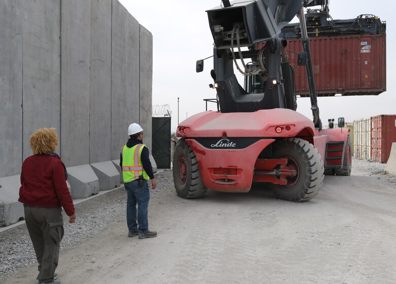 Tina Byrd, Afghanistan District Supply Specialist, guides the Safety Officer as the Big Lift removes an empty container from the USACE Afghanistan District supply yard in an effort to downsize excess storage units.