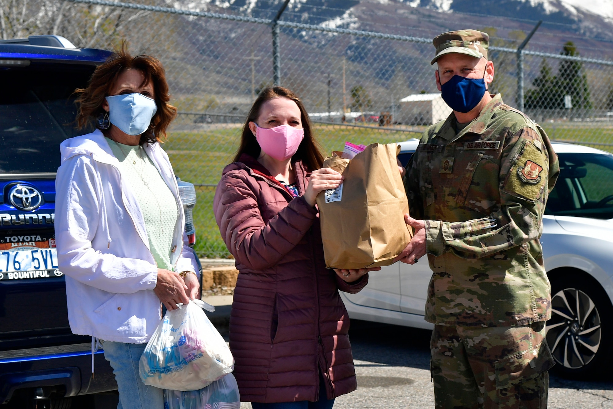 Joy Gingrich and Sarah Web, community volunteers, present Chief Master Sgt. Christopher Walker, 75th Air Base Wing Command Chief, with thousands of homemade face masks for the base military and civilian Airman personnel.